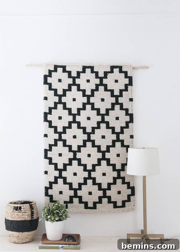 A black and white painting hanging on a white wall with a lamp and vase near it