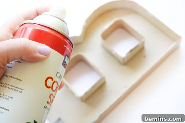 A person holds a can of non-stick cooking spray, demonstrating the crucial step of preparing the molds for easy cement release.