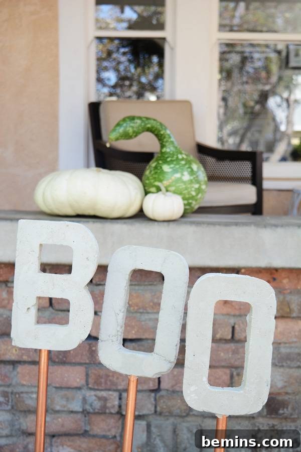 The word "BOO" as garden art made of concrete letters on copper stakes, a playful Halloween decoration.