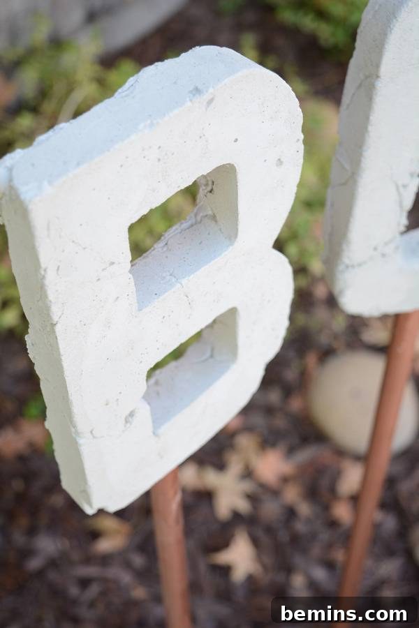 Close-up of the letter 'B' from a typographic concrete garden art, showcasing its raw, durable finish.
