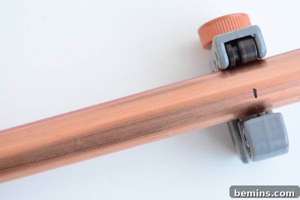 A pink and grey pipe cutter tool resting on a white surface, demonstrating the simplicity of cutting copper pipe.