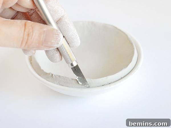 Neatening the edges of the clay bowl