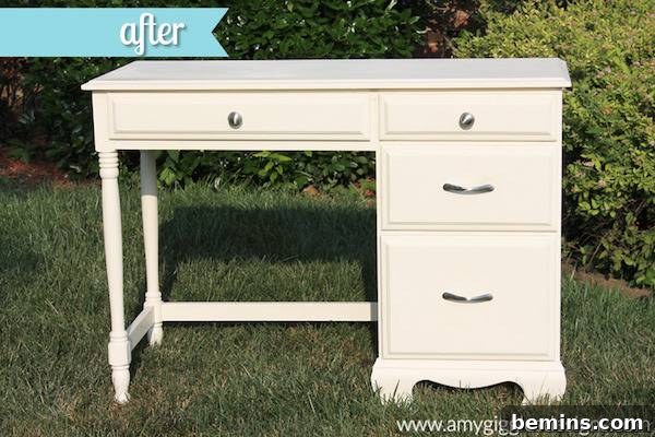 A cream colored desk sits outside in the grass.