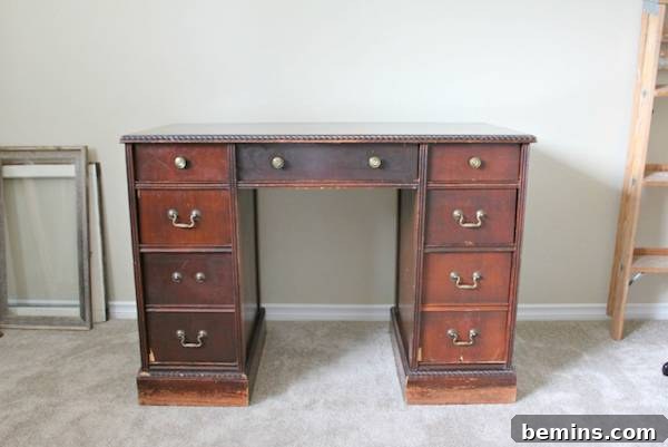 An old wood desk is next to a ladder and picture frames.