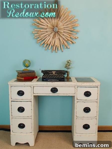 1950's style beige desk has a typewriter and some books on it.