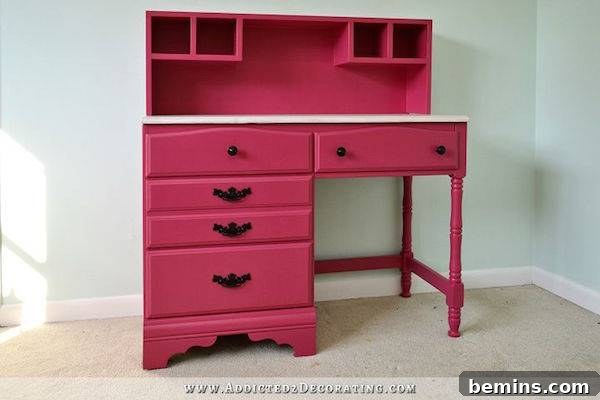 A pink desk is sitting against a light blue wall.
