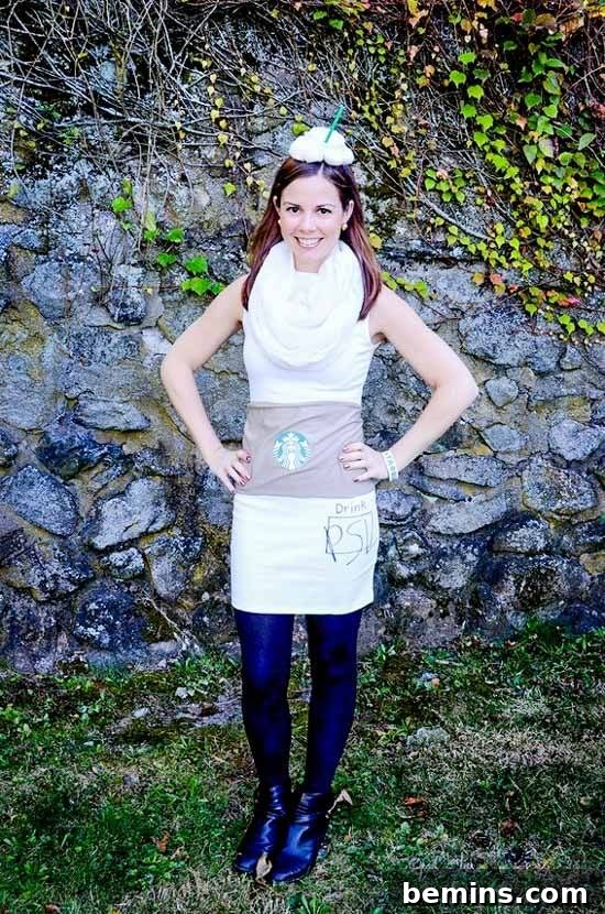 A woman dressed as a Pumpkin Spice Latte, posing confidently in front of a rock wall, showcasing the completed costume.