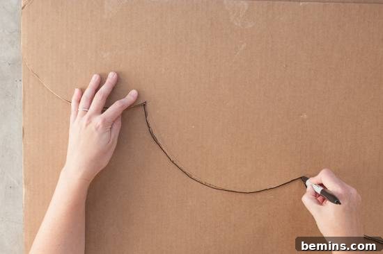Craft Your Own Bird Costume: A Step-by-Step Guide 4 A right hand holding a black marker that has drawn a couple of troughs and a left hand holding down the cardboard.
