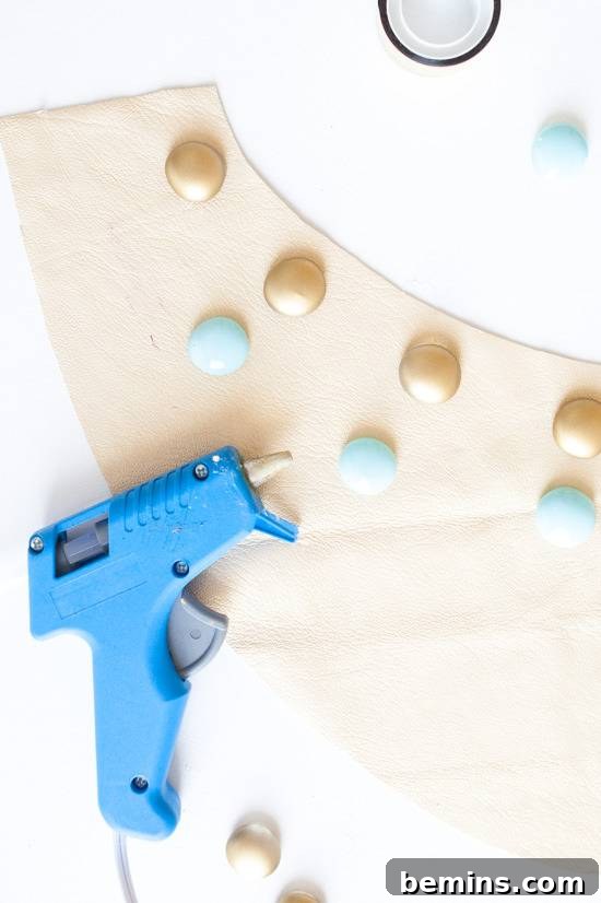 A glue gun is laying on decorative paper and items.