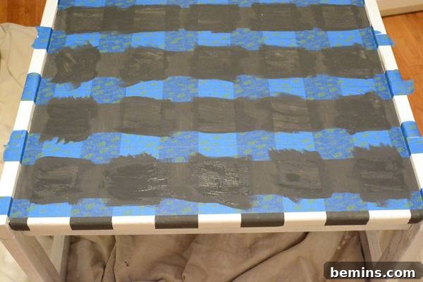 White table sitting on top of a grey sheet with blue tape and black tape on its surface.