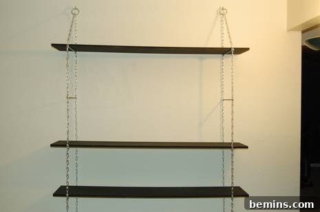 Hanging bookshelf with wooden racks and chains.