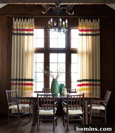 Visual Delight: 10 Modern Yet Cozy Cabins Perfect for a Woodland Escape 7 Dining area with chairs, a table near a large window, and wool blanket curtains.