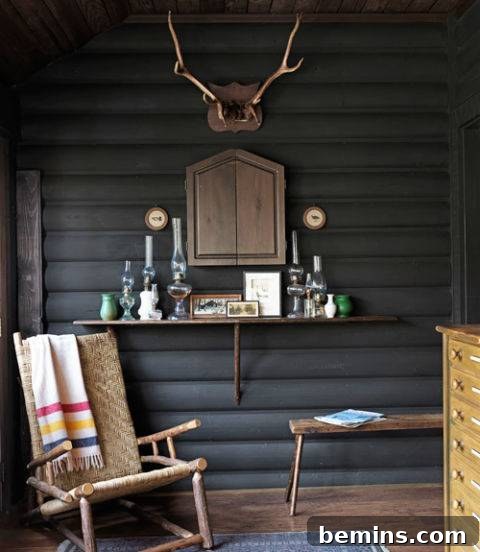 Visual Delight: 10 Modern Yet Cozy Cabins Perfect for a Woodland Escape 8 Front porch with a wicker rocking chair, grey log wall, antlers, and candles.