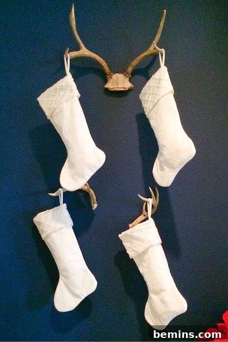 White stockings hanging from a blue wall on deer antlers.