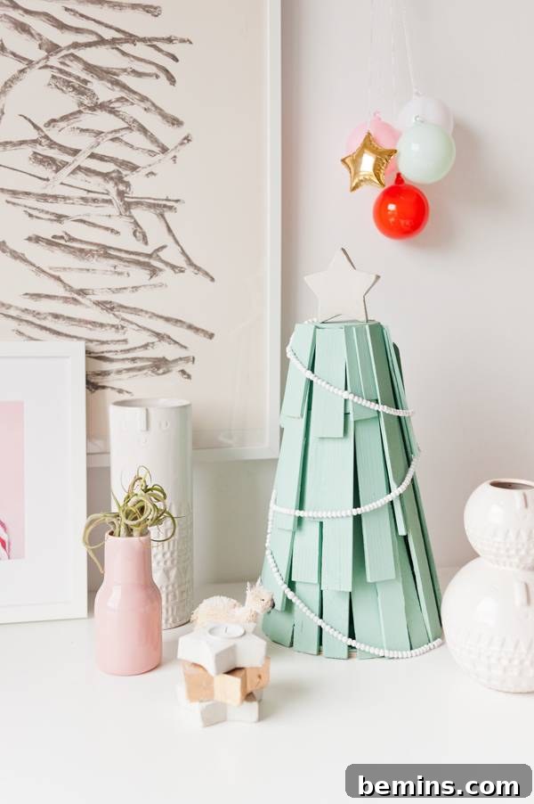 Wood shims shaped into a Christmas tree shape with light green paint and ornaments.