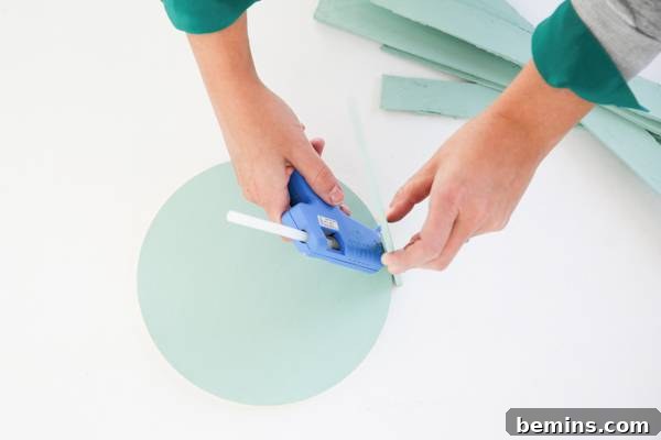 A person is gluing a circle-shaped painted wood piece with a rectangular painted wood piece.