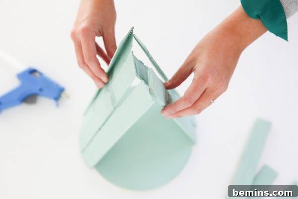 A person is working to assemble a light blue craft project.