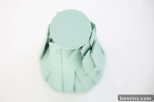 A tabletop Christmas tree stand made from small pieces of wood painted green is shown.