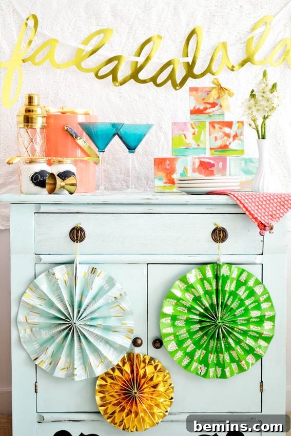 Unconventional Christmas Decor: 11 Fresh Color Palettes 12 A gold falalalal sign hanging on the wall above a light blue side table with two blue martini glasses on top of it.