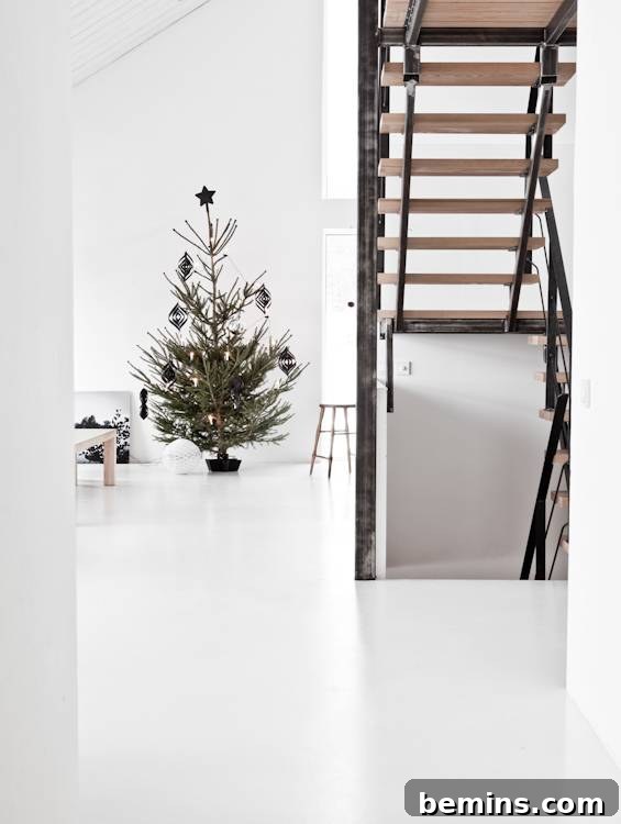 Unconventional Christmas Decor: 11 Fresh Color Palettes 13 A white living space with a Christmas tree and stairs, showcasing a minimalist black and white theme.