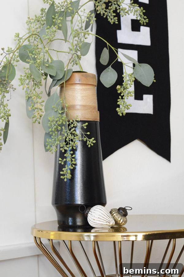 A black banner hanging on the wall above a gold side table, showcasing a stylish holiday display.