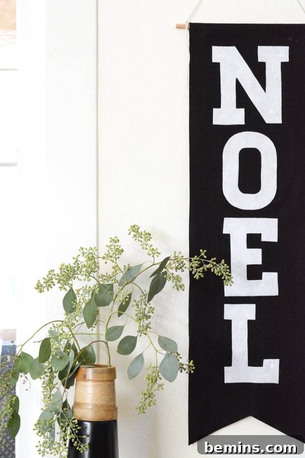 The finished NOEL banner hanging on a white wall, adding a festive touch.