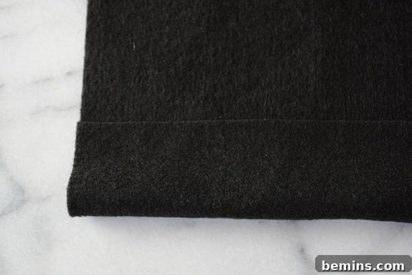A black towel on a white marble floor, showing the fabric after the sleeve is created.