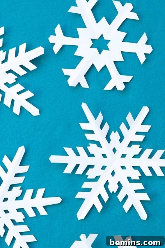 A collection of pristine white paper snowflakes against a calming blue backdrop.