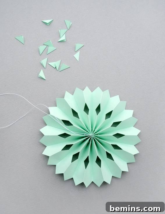 A light green paper medallion, showcasing intricate diamond cutouts.