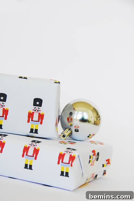 Two beautifully wrapped gift boxes featuring a charming nutcracker pattern, alongside a decorative round steel ball, embodying classic holiday elegance.