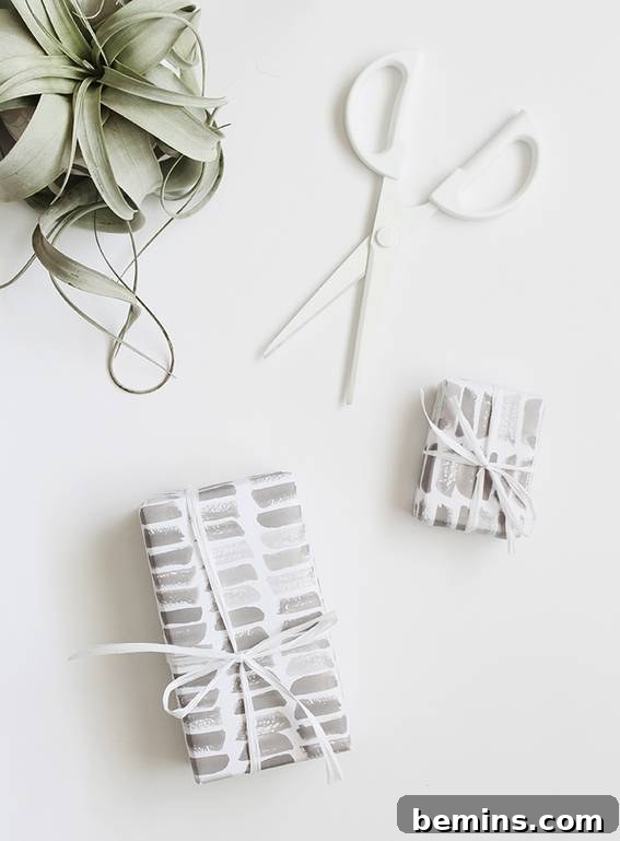 Artistically printed gift wraps featuring minimalist designs, alongside white scissors and a small potted plant, all set on a clean white background, showcasing a sophisticated approach to gift presentation.
