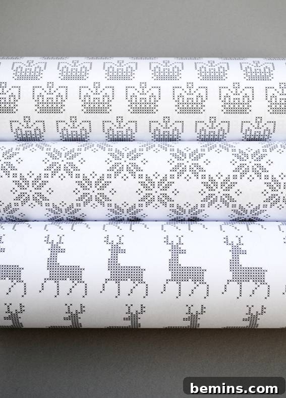 Three elegant rolls of silver and white cross-stitch pattern wrapping paper, showcasing a festive and handcrafted aesthetic perfect for holiday gifts.