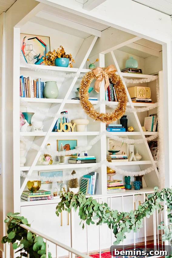 A shelving unit beautifully decorated for Christmas with a mixture of live greenery and shimmering tinsel.