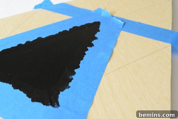 Tape outlines a painted Christmas tree, demonstrating the taping and painting process.