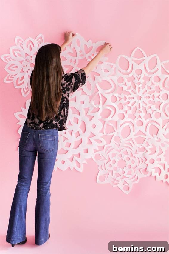 White origami flowers on pink wall - DIY Holiday Photo Backdrop