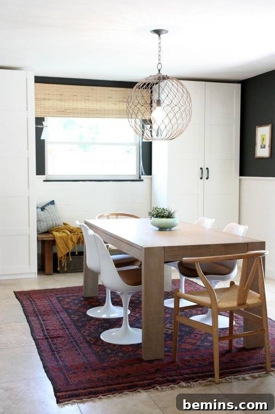 A wooden table with white chairs is sitting on a red rug in a kitchen.