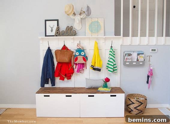 White mudroom storage display with hooks for coats and drawers for storage.