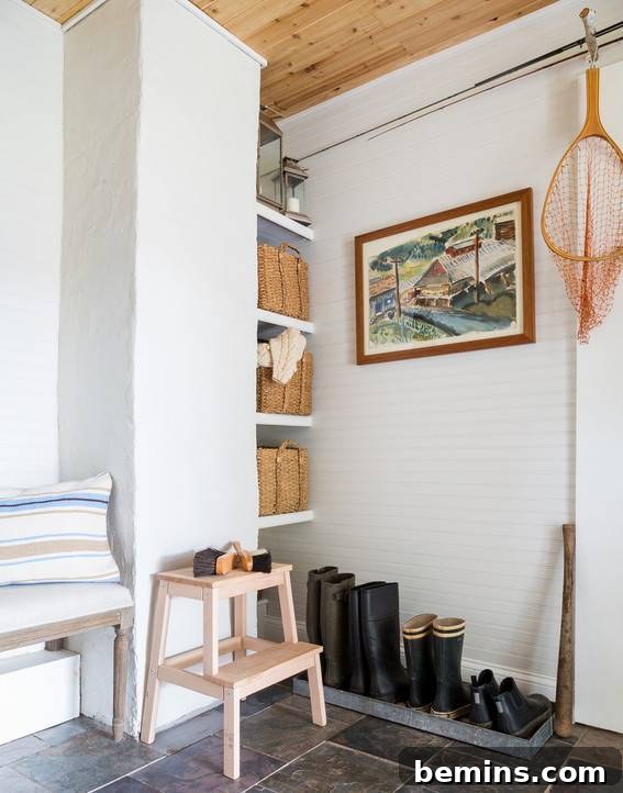 Shoes and boots are lined up against a wall under a picture.