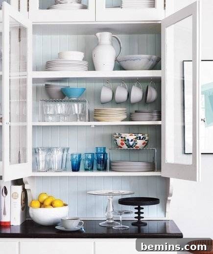 Well-organized white kitchen cabinets showcasing various bowls and glasses.