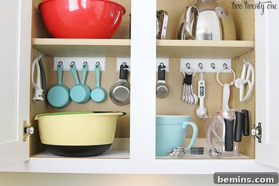 Organized baking cabinet with measuring cups, bowls, and essential baking supplies.