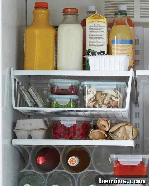 Refrigerator with bottles and groceries organized using repurposed cabinet organizers