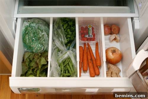 Vegetables neatly sorted into different sections of a refrigerator drawer using dividers