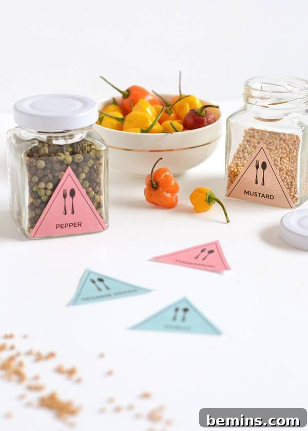 A close-up showcasing pepper and mustard seeds stored in separate glass jars, each clearly labeled with its name, alongside a bowl of vibrant cherry capsicum.