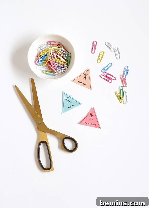 A white table featuring scissors, paper triangles, and a bowl filled with paperclips, illustrating the creative process of organization and labeling.