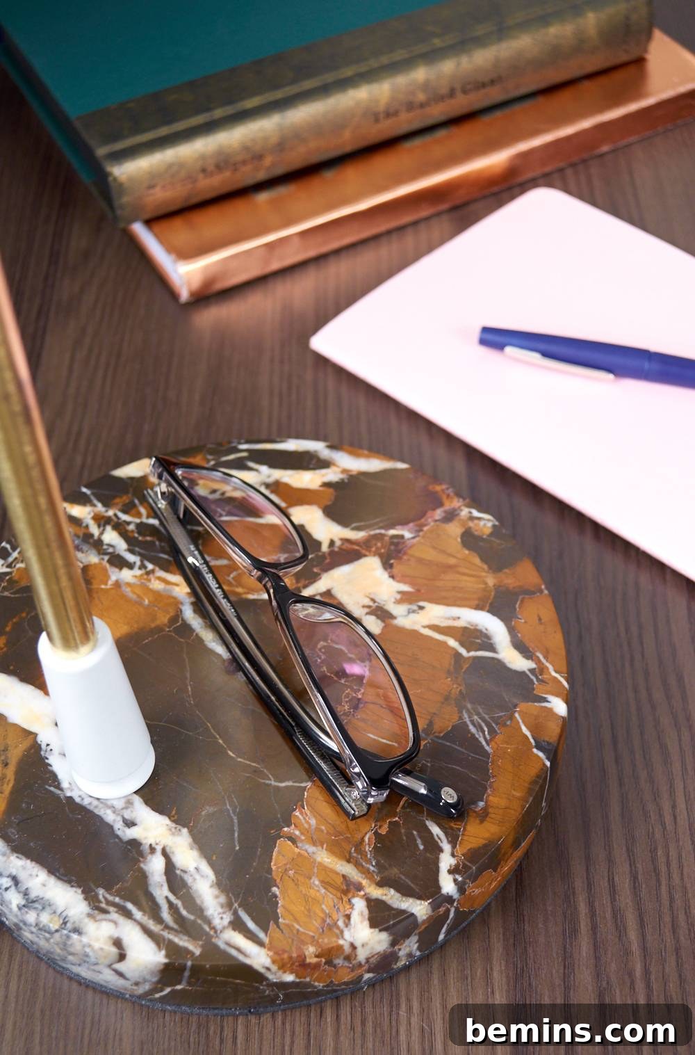 Eyeglasses resting on an object near a paper and blue pen