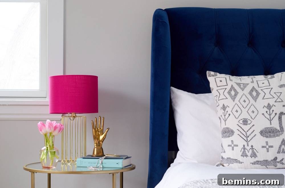 Glass nightstand with pink lamp, plant, book, and gold hand statue