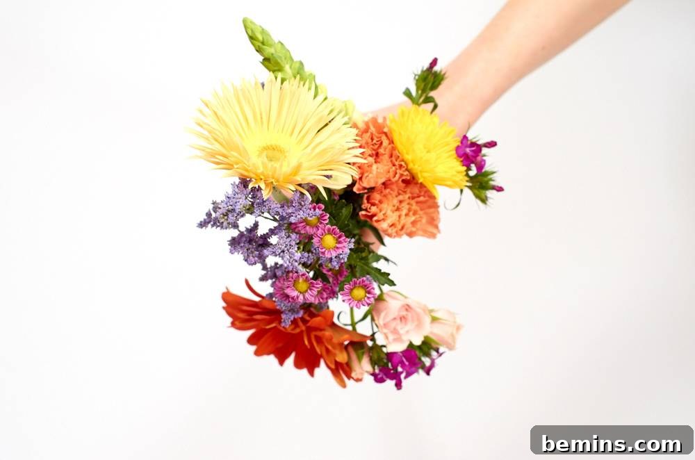 A hand holding a variety of colorful flower stems.
