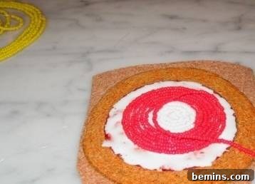 A partially completed candy corn coaster, showing the white center and the first ring of orange seed beads being carefully glued onto a cork base.