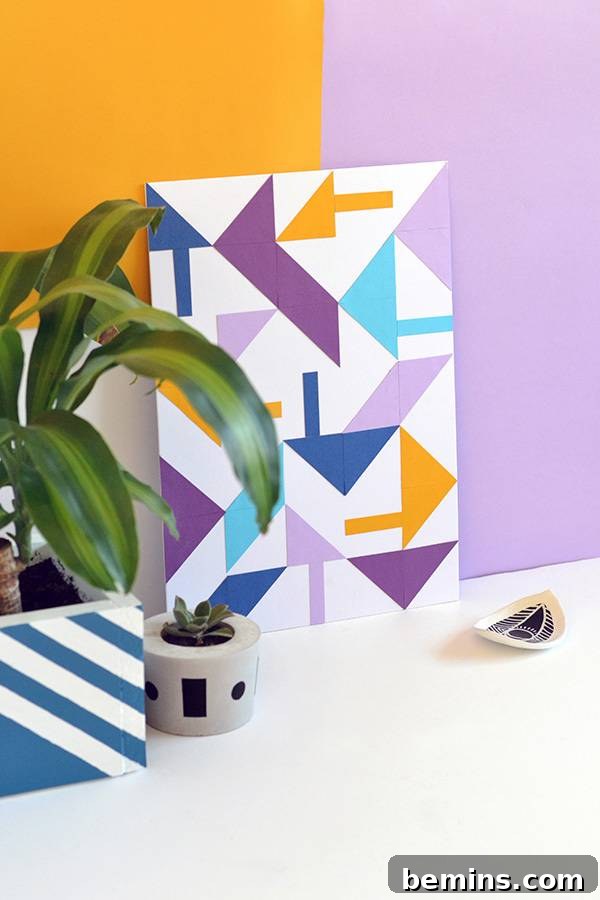 A vibrant geometric paper art print with arrow motifs, displayed casually next to a green houseplant on a shelf