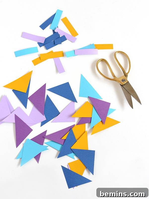 An array of colored paper shapes including squares, triangles, and thin strips, prepared for assembly
